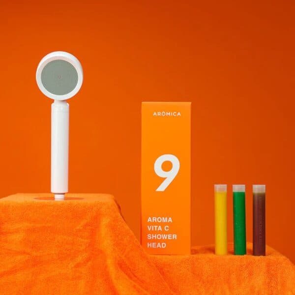 Aroma Vita C Shower Head with colorful test tubes, vibrant orange background, modern design, and packaging, highlighting air and water purification for healthy skincare and shower experience.