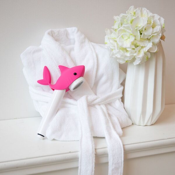 Pink dolphin-shaped showerhead on white towel with white hydrangea flowers in vase, bathroom decor, shower accessories, cute and functional bathing tools, bathroom aesthetic, bathroom essentials, baby shower gift idea.