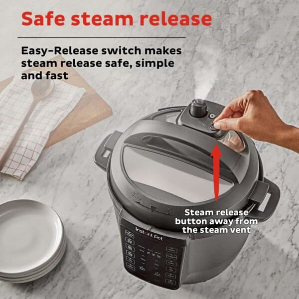 Safe steam release, instant pot with steam release button held away from steam vent, kitchen countertop, easy pressure cooker safety feature, image for cooking safety tips, pressure cooker steam safety.
