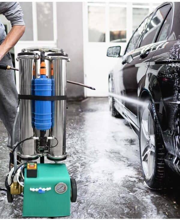 High-pressure car wash system with water jets cleaning a black vehicle at an auto detailing station. Professional-grade equipment used for vehicle cleaning and maintenance.